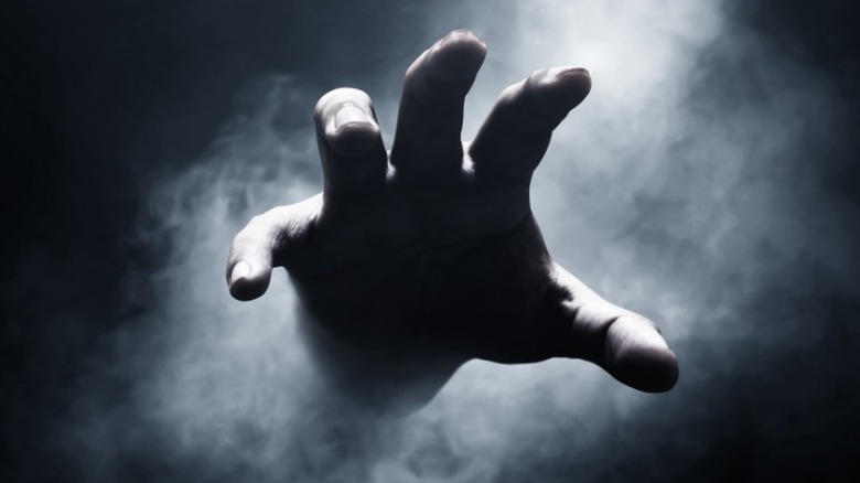 creepy hand reaching out of dark