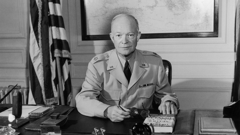Dwight Eisenhower at his desk holding his glasses