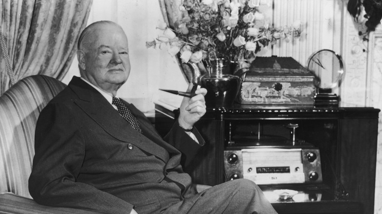 Herbert Hoover seated in a chair with his pipe