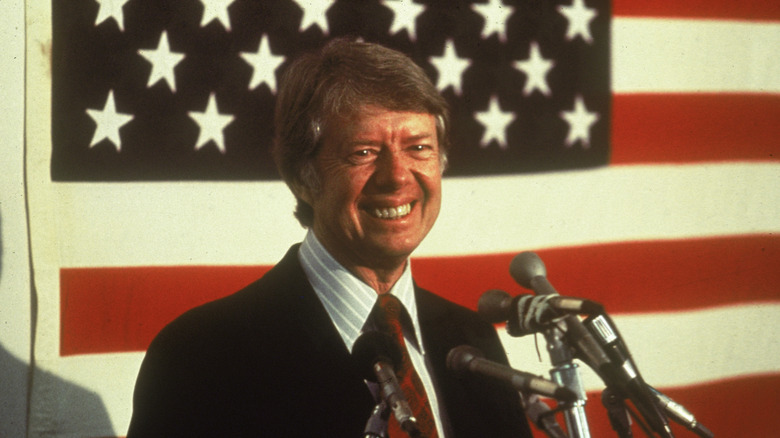 Jimmy Carter smiling in front of microphones
