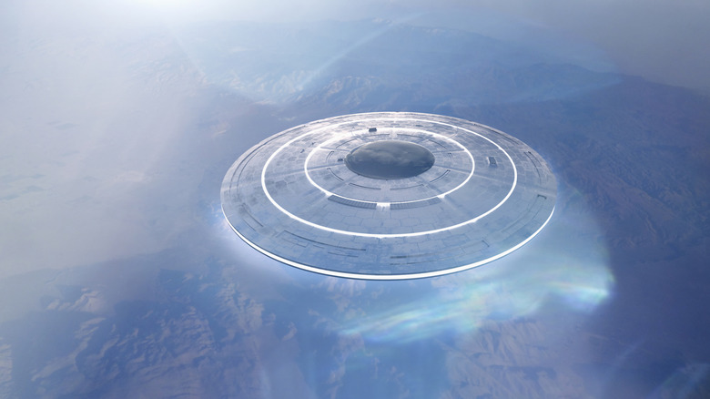 Computer illustration of flying saucer above mountains, overhead view.