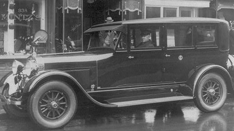 Chauffer-driven Lincoln Model L used by Calvin Coolidge parked in front of stores