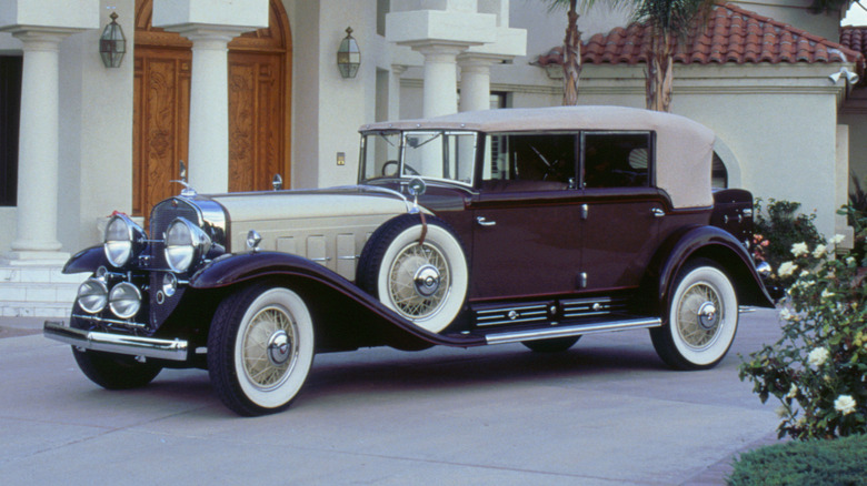 A modern photo of a 1932 Cadillac V16 outside a mansion