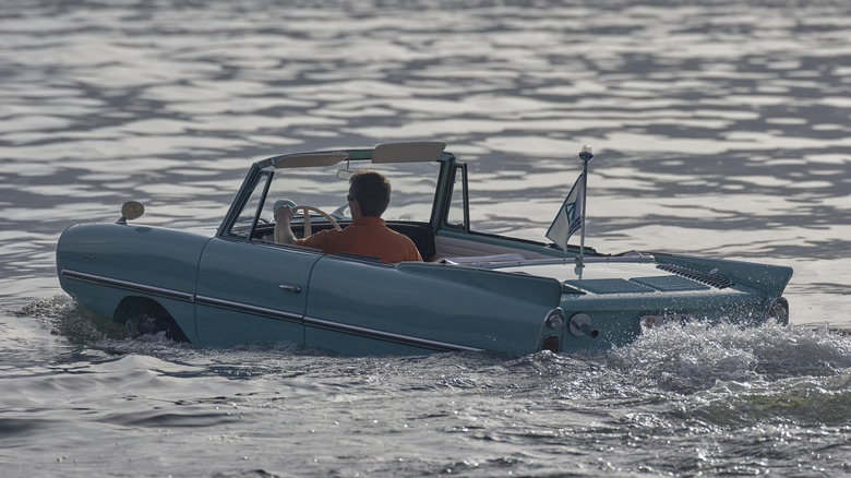A man driving an Amphicar on a body of water