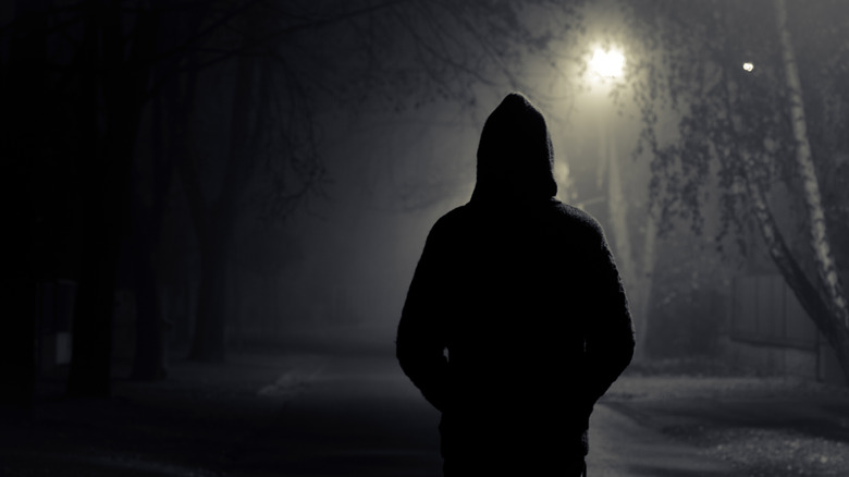 Silhouette of hooded man on dark street