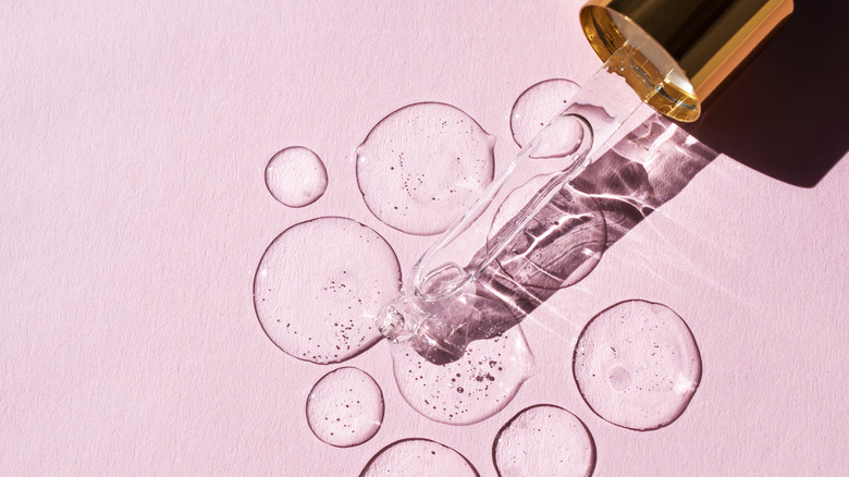 Liquid droplets from pipette on pink background