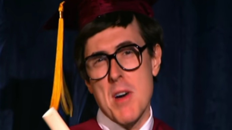 A still image shows Weird Al Yankovic in a graduation cap and gown from the White & Nerdy video.