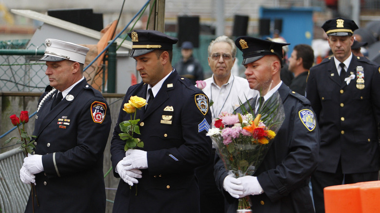 NYPD, FDNY, and Port Authority personnel at memorial with flowers