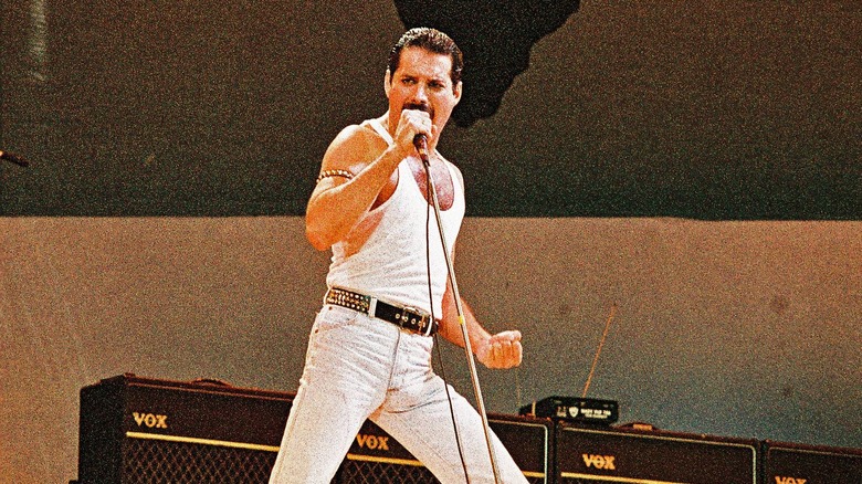 Freddie Mercury singing on stage in white vest