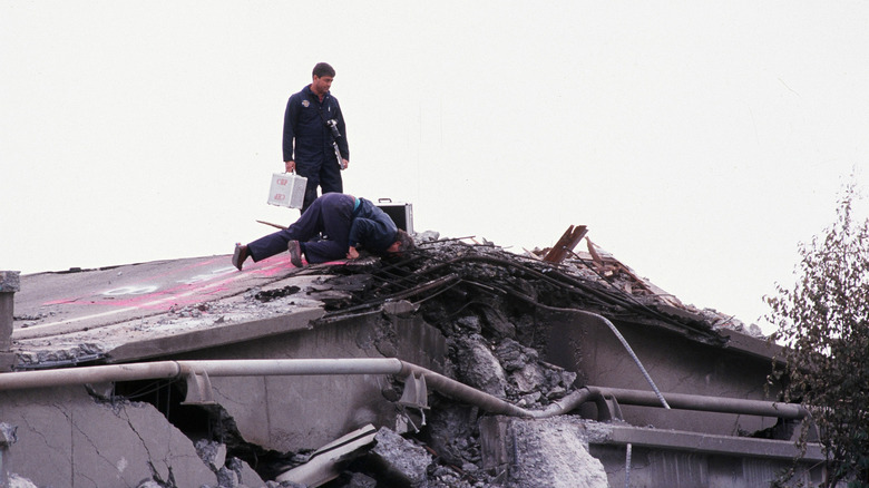 workmen inspect a damaged highway