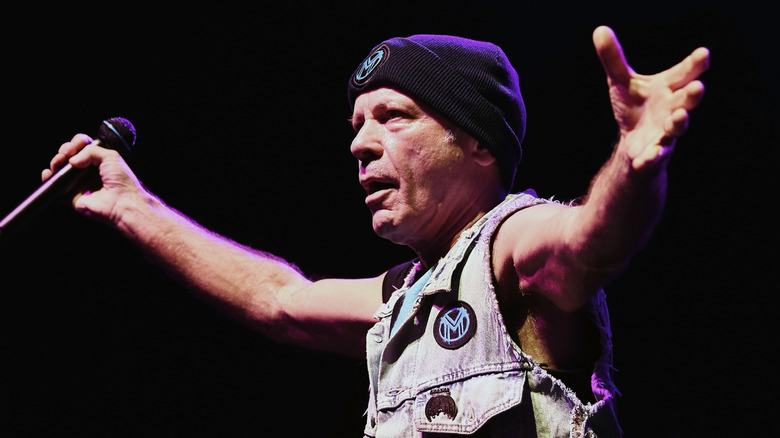 Bruce Dickinson spreading his arms onstage holding a microphone