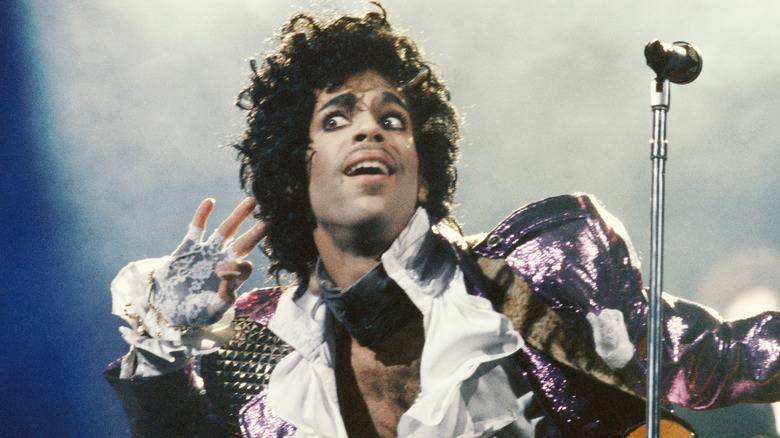 Prince performing onstage holding a hand to his ear