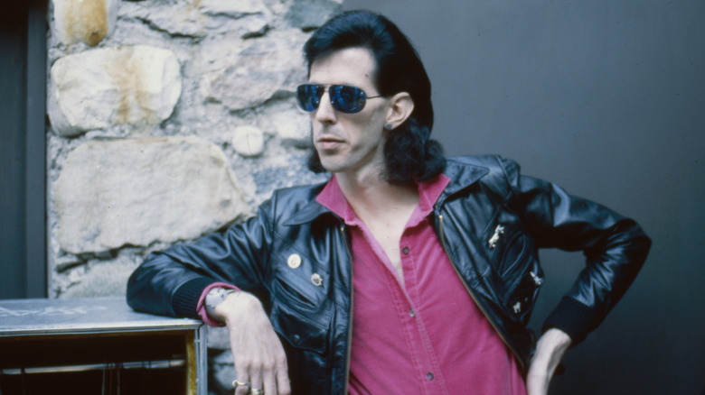 Ric Ocasek in a black leather jacket and sunglasses posing for a photo