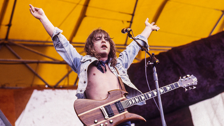 Rick Derringer with his hands raised onstage