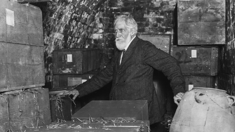 Archeologist Petrie walks through boxes of artifacts