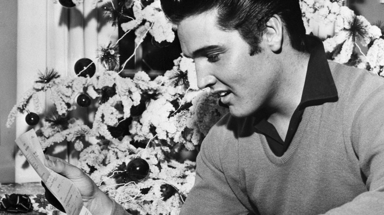 Elvis reads before a Christmas tree