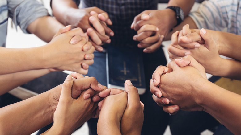 people holding hands over bible