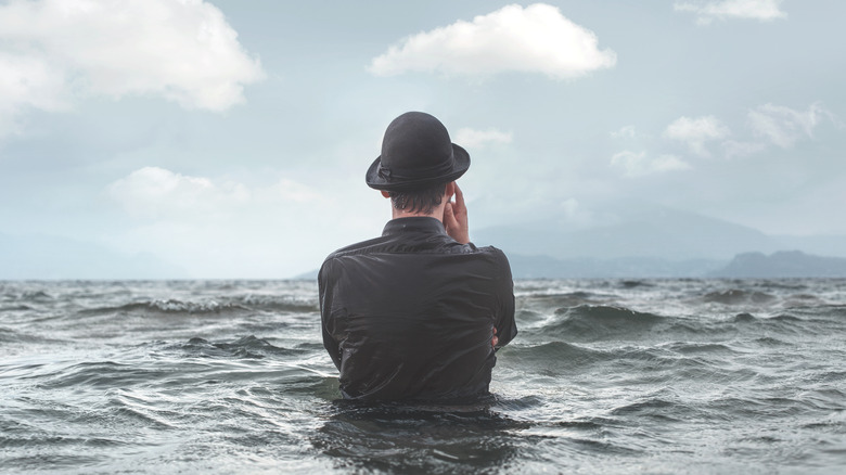 Clothed man stands in sea 