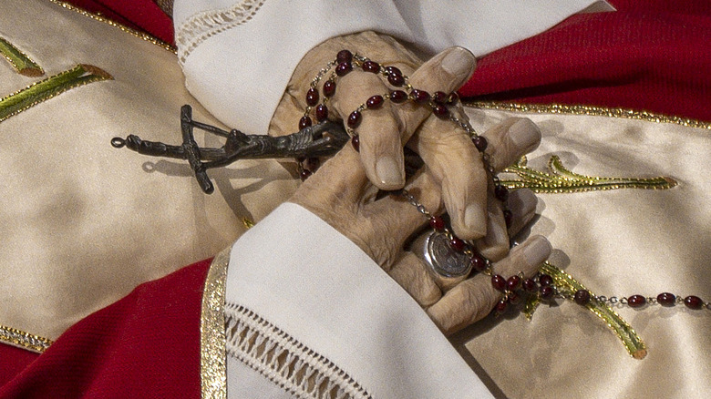 Benedict XVI's hands clasp a rosary and crucifix