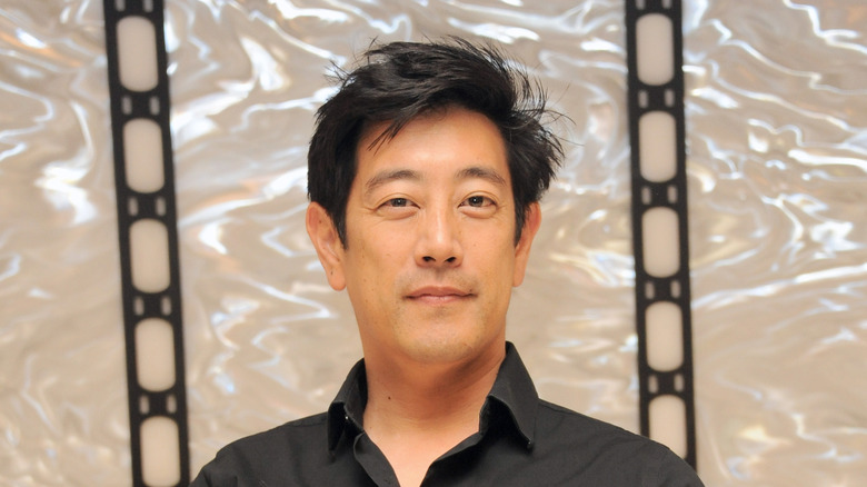 Grant Imahara smiling slightly and staring into camera