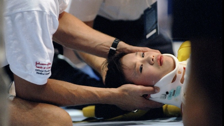 sang lan in lying down in neck brace man holds neck