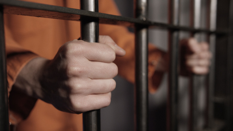 man's hands on prison bars