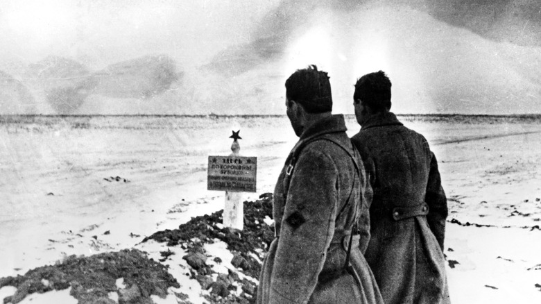soldiers looking at mass grave 
