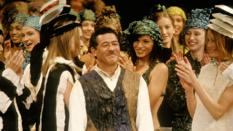 Issey Miyake surrounded by clapping models at his fashion show