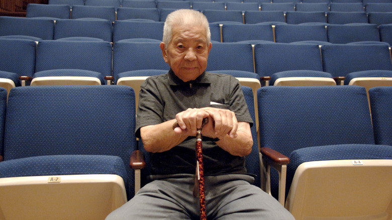 Tsutomu Yamaguchi sitting in an empty auditorium