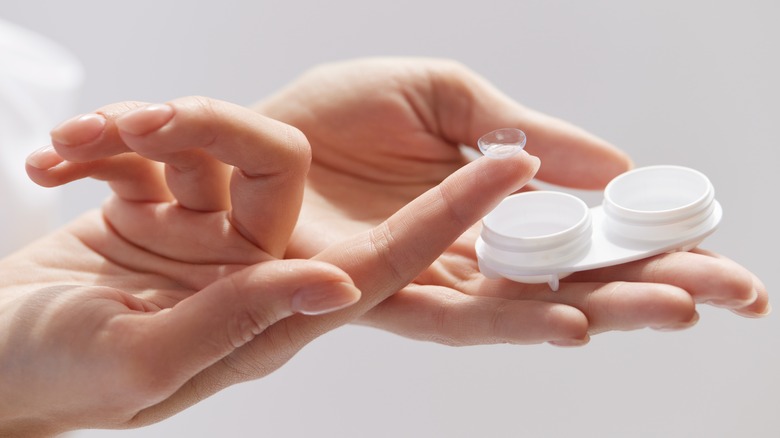 hands holding contact lenses and case