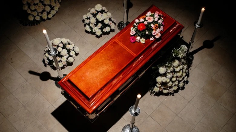 Coffin surrounded by flowers and candles