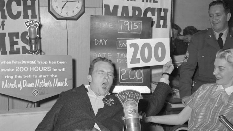 WMGM disc jockey Peter Tripp yawns and holds up a sign reading "200" after going 200 hours without sleep