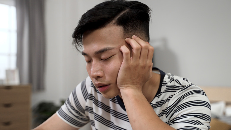 Young man nodding off with head in hand, closeup.
