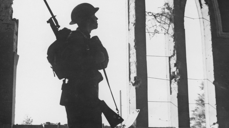 Soldier silhouetted against bombed-out window in England after Luftwaffe raid, August 1940