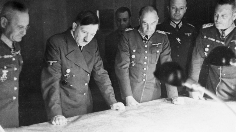 Hitler and Nazi officer study map on table