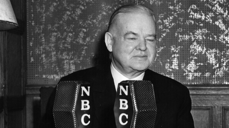 Herbert Hoover stands behind microphones