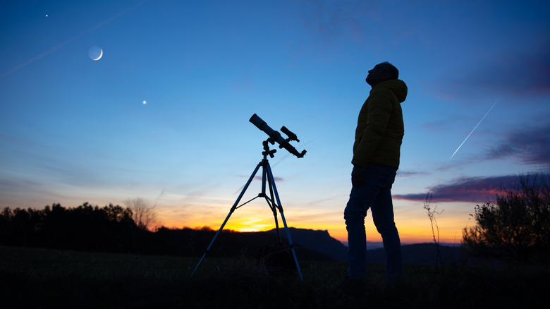 astronomer standing by telescope at night