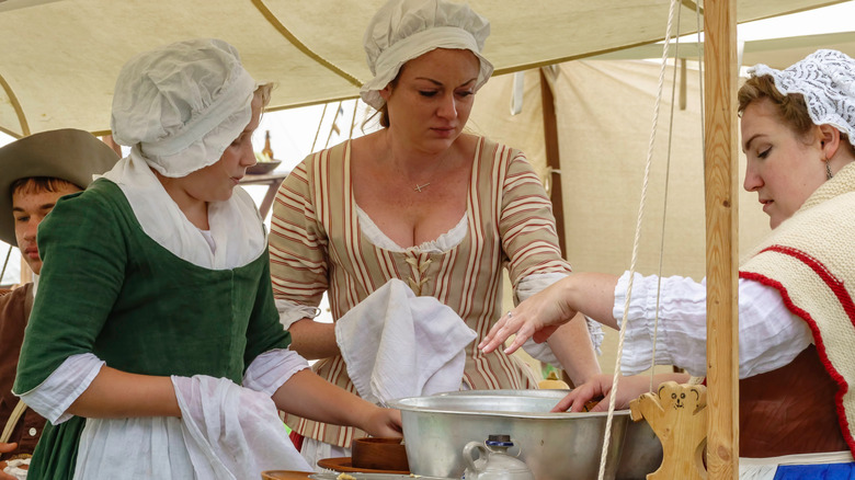 Three women washing dishes at Revolutionary War re-enactment camp