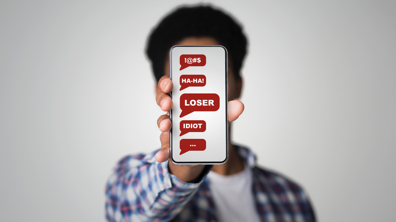 person holding phone with insults on screen