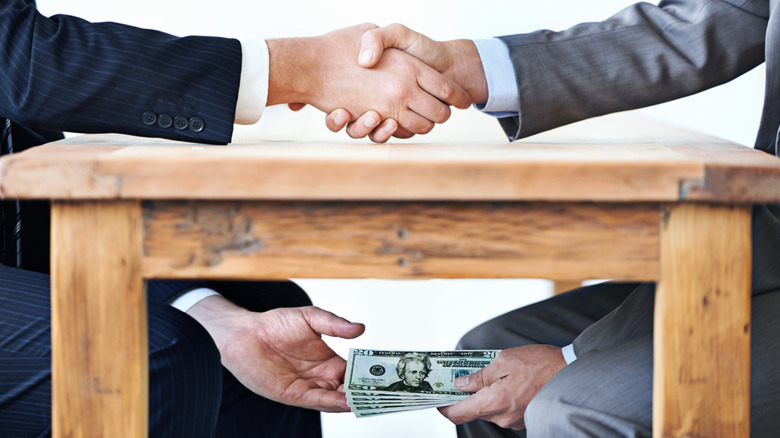 Businessmen shaking hands and exchanging cash