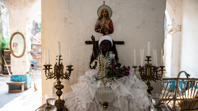 Santeria altar candle doll with beads on table with candlesjesus ceramic