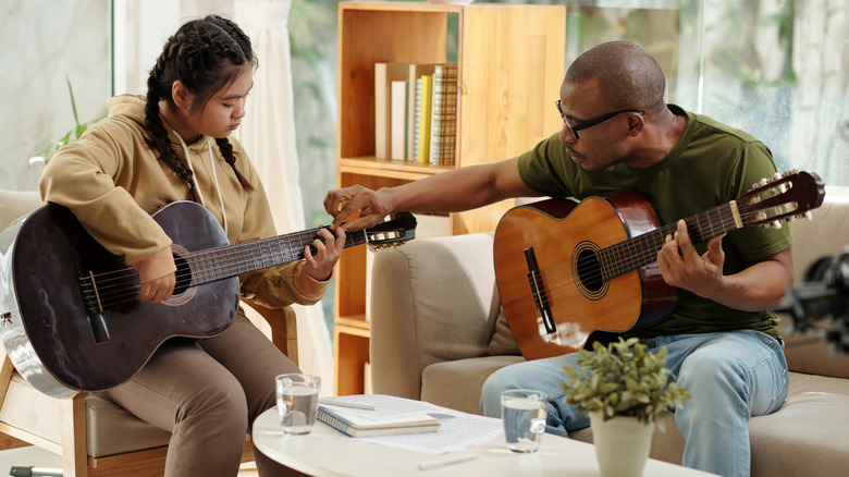 Teacher teaching guitar to girl