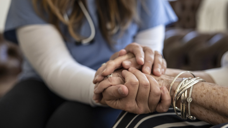 Nurse holds old woman's hands