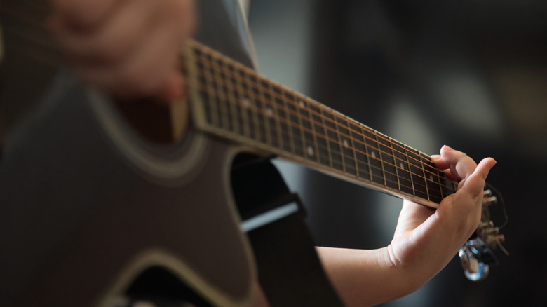 Close-up person playing acoustic guitar