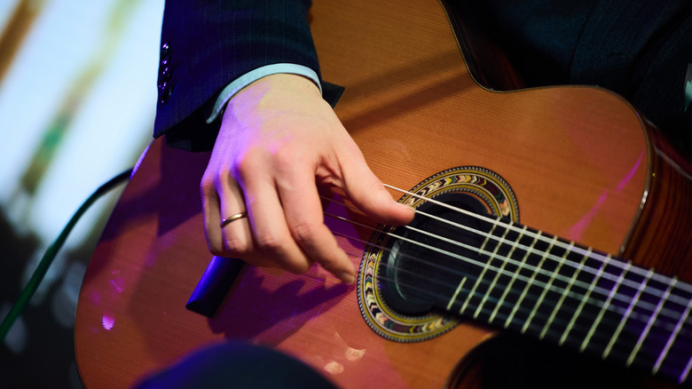 A close-up of someone's hands playing an acoustic guitar.