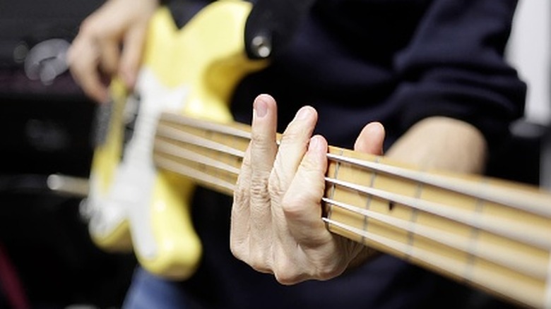 A musician playing a yellow bass guitar.