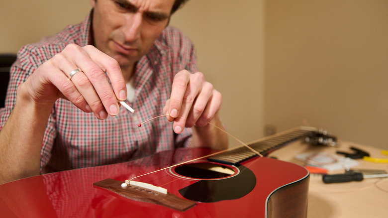 Man restringing red guitar