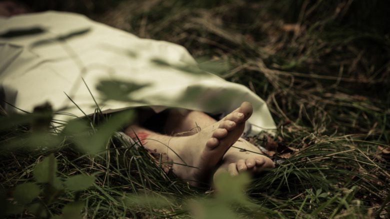 feet poking out of sheet in grass