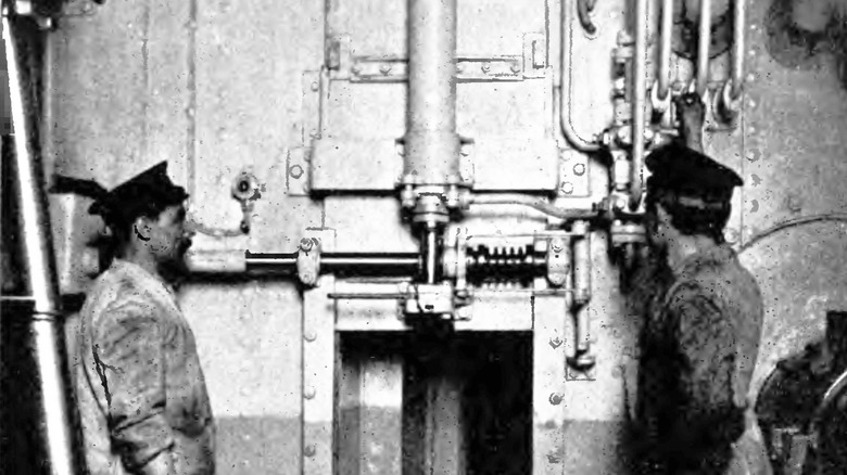 two crew members standing looking at hydraulics