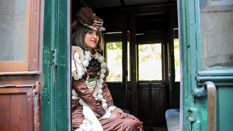 Woman in 1800s clothing sitting in an old train